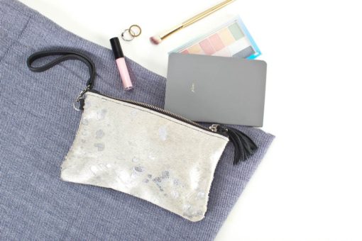 A silver purse with some makeup and a laptop