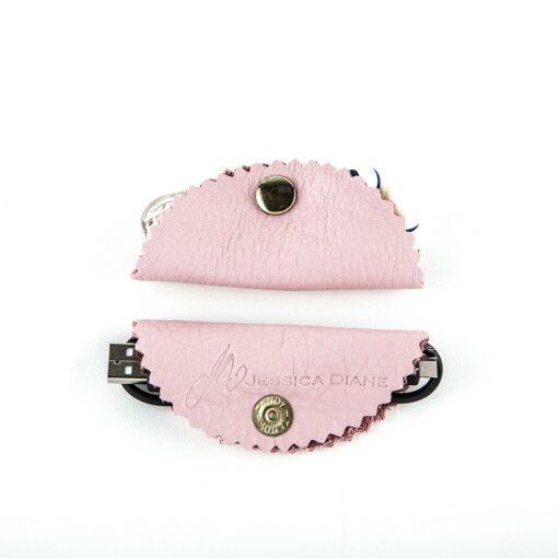 A pair of pink leather hair clips with a black and white design.