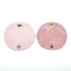Two pink circular coasters with a gold metal holder.